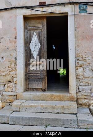 Guardando attraverso il vecchio apri porta di legno alle tenebre e piccola patch di luce di distanza Foto Stock