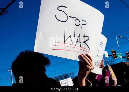 La guerra protestor - Uomo su angolo di strada mantenendo la ferma la guerra segno con altri manifestanti in distanza Foto Stock