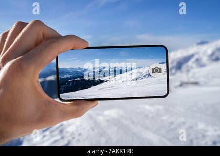 Mano d'uomo prendendo Fotografia di montagne innevate sul telefono cellulare Foto Stock