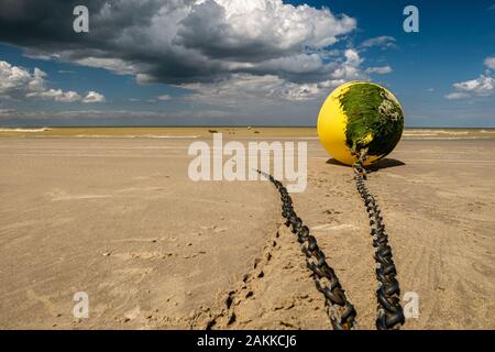 Bassa angolazione di una boa giallo coperto con alghe legata alla spiaggia di attesa per la prossima alta marea Foto Stock