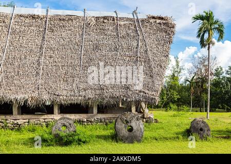 Con il tetto di paglia tradizionali yapese uomini meeting house chiamato faluw o fale e una banca di tre storica pietra megalitico denaro rai nella parte anteriore di essa. Alta co Foto Stock