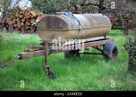 Agricola vecchio arrugginito rimorchio con un serbatoio di acqua su di esso Foto Stock