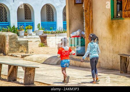 Isola di Goree, Senegal- 22 aprile 2019: ragazze non identificato a piedi lungo una strada di sabbia in una piccola città. Foto Stock