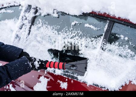 Donna di pulizia auto da neve dopo la nevicata Foto Stock