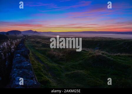 Guardando ad ovest accanto al generale Wade's strada militare (B6318) che costeggia il Vallum del muro romano in Northumberland Foto Stock