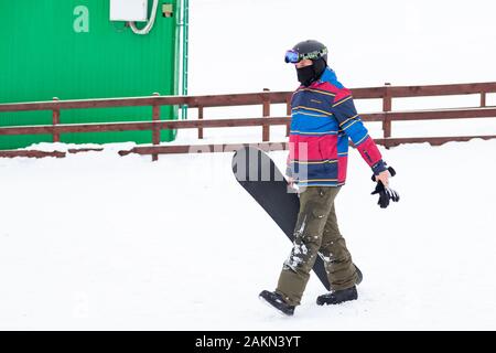Altai, Russia - 01.01.2020: un uomo snowboarder andando scorre giù per la montagna più bianco della neve in uno sport di base turistica turchese Katun. Sport stagionale Foto Stock