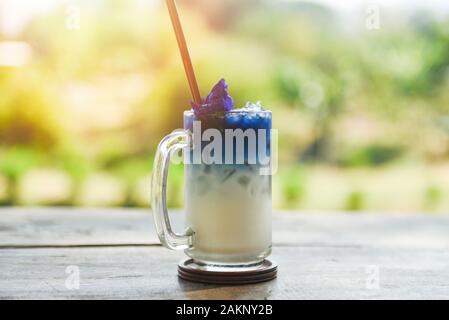 Bevanda di butterfly pea bere un bicchiere in legno con la natura sfondo verde / blu ghiacciata pea fiore di latte e succhi di frutta in estate Foto Stock