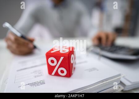 Close-up di Rosso Blocco cubico con simbolo di percentuale di fronte commercianti calcolo fattura Foto Stock