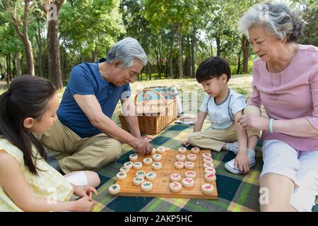 La famiglia felice all'aperto giocando a scacchi Foto Stock