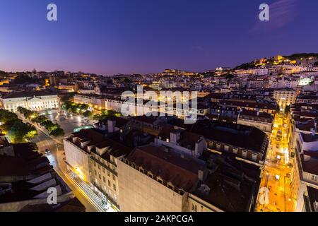 Vista della Piazza Rossio (Praca do Rossio), dei quartieri Baixa e Alfama e della strada Rua de Santa Justa verso Castelo de Sao Jorge a Lisbona al tramonto. Foto Stock