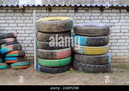 Vecchi pneumatici verniciati per camion. Molti pneumatici colorati contro un muro di mattoni bianchi. Fuori Senza nessuno Foto Stock