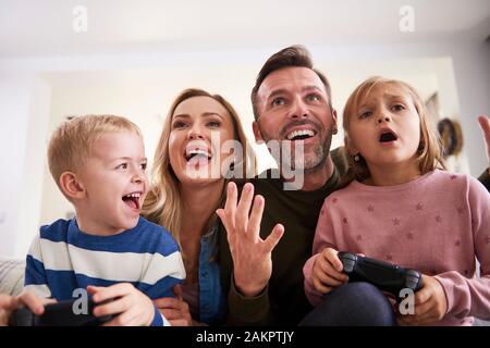 Emotional i genitori e i bambini che giocano con i video game a casa Foto Stock