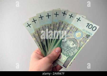 gamma di cento note di zloty lucidante tenute in mano. Foto Stock