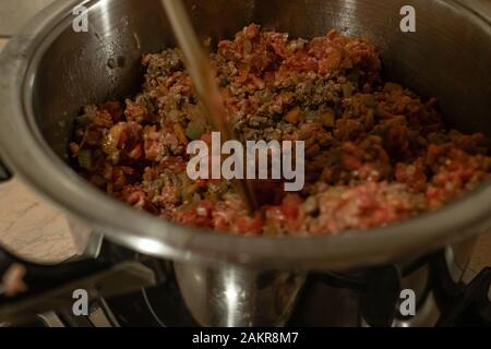 In prossimità di una pentola in acciaio pieno di carne carote cipolla e sedano per italiano preparazione ragu Foto Stock
