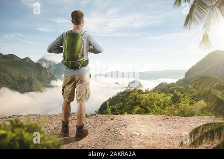 Escursionista su una montagna che si affaccia su un paesaggio tropicale Foto Stock