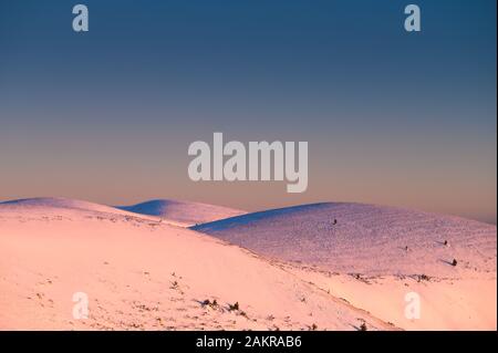 Bianco colline coperte di neve sotto cielo blu, spazio di montaggio. Foto Stock