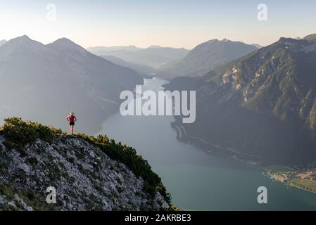 Giovane donna che si affaccia su un paesaggio di montagna, vista dal monte Baerenkopf al Lago Achensee, sinistra e Seebergspitze Seekarspitze, destra Rofan Foto Stock