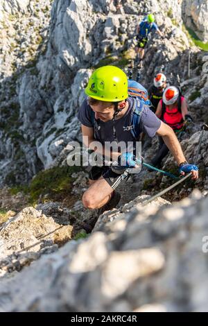 Alpinista con casco su un assicurato via ferrata, Mittenwald via ferrata, montagne Karwendel, Mittenwald, Germania Foto Stock