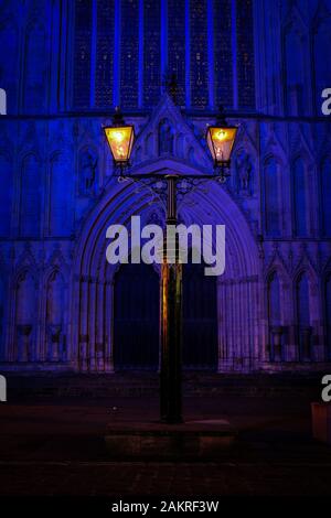 York, Regno Unito. In vecchio stile lampade al di fuori del West End porte di York Minster illuminata di notte. Foto Stock