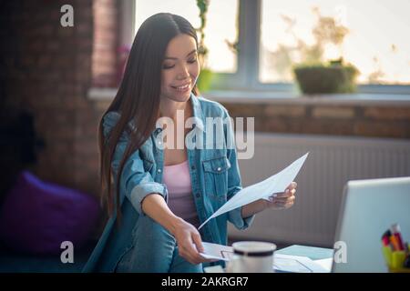 Bella donna allegra concentrandosi sul suo lavoro Foto Stock