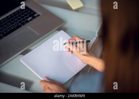 Bella giovane donna tenendo una matita durante il disegno Foto Stock