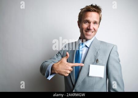 Imprenditore sorridente rivolta con un allegro espressione al suo nome vuoto tag Foto Stock