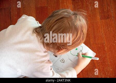 Bambino disegna un albero sul pavimento in legno Foto Stock