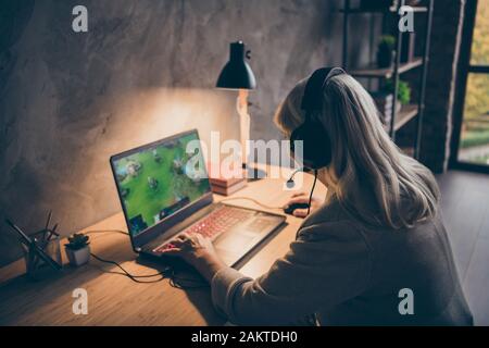 Profilo vista laterale ritratto di lei bella bella messa a fuoco bionda capelli grigi nonna giocare online gioco di squadra in remoto su PC a loft industriale Foto Stock