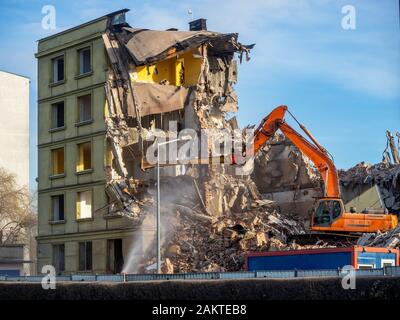 Demolizione di un vecchio edificio di uffici in modo tradizionale utilizzando un escavatore Foto Stock