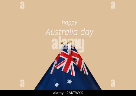 Primo piano di alcuni flag australiano e il testo happy australia giornata contro una luce sfondo marrone Foto Stock