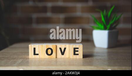 Il messaggio di amore scritte in blocchi di legno. Sfondo mattone Foto Stock