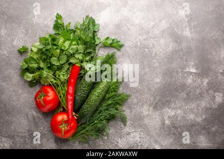 Diverse verdure fresche, pomodori, cetrioli e peperoncino su un cemento grigio Sfondo. Vista dall'alto. Copia dello spazio. Foto Stock