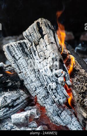 Caldo e invitante primo piano di fuoco buca legno combustione con fiamma e cenere Foto Stock