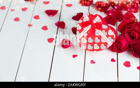 Scatola regalo a forma di cuore e rose rosse sul tavolo di legno bianco Foto Stock