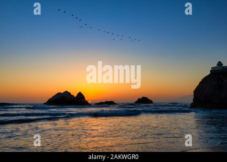Il sole che tramonta su Seal Rock lungo la costa californiana di San Francisco mentre le onde si infrangono in un pomeriggio limpido Foto Stock