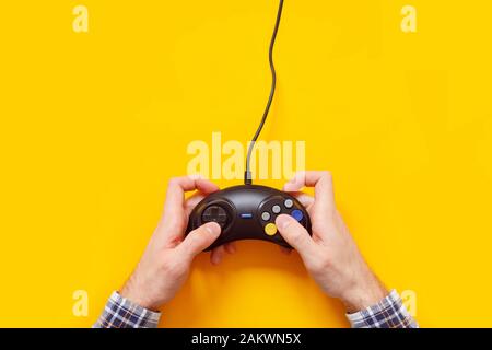 Mani dell'uomo con vecchio gamepad cablato isolato su giallo Foto Stock