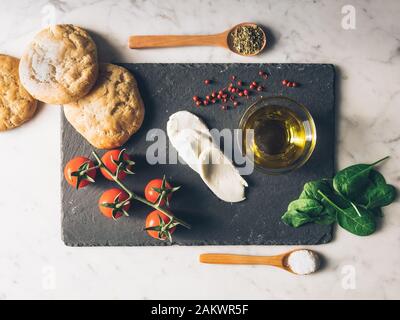 Vista superiore del cibo italiano ingredienti : olio, pane fresco di pomodori ciliegini, mozzarella. una sana dieta mediterranea. Burger di italiano Foto Stock