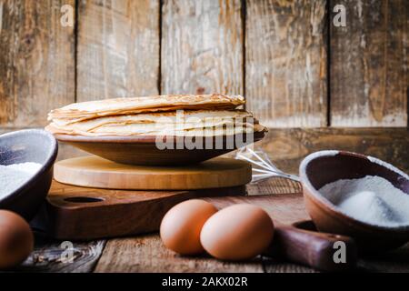 Crepes blini, facendo frittelle sottili, ingredienti, rustico tavolo in legno Foto Stock