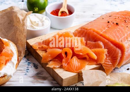 Brunch festivo con salmone curato servito con formaggio cremoso, bagel, pentola di caviale di salmone, avocado, rustico tavolo vicino Foto Stock