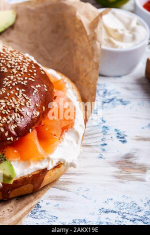 Brunch festivo con salmone curato servito con formaggio cremoso, bagel, tavolo rustico da primo piano Foto Stock
