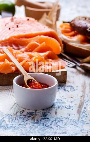 Brunch festivo con salmone curato servito con formaggio cremoso, bagel, pentola di caviale di salmone, avocado, rustico tavolo vicino Foto Stock