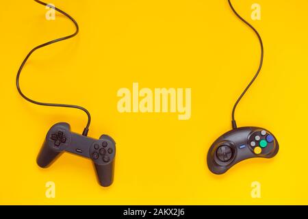 Due gamepad cablati o controller di gioco video su sfondo giallo. Vista dall'alto, piatto. Gaming, settore della console. Foto Stock