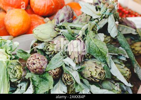 Carciofi freschi crudi biologici crudi verdure con foglie in vendita presso il mercato o negozio degli agricoltori locali. Cibo vegano e sano concetto di nutrizione. Scorte Foto Stock