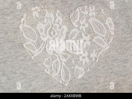 Tessuto in Jersey grigio con cuore in pizzo bianco per lo sfondo Foto Stock