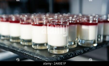 Primo piano di mini dessert cheesecake serviti in piccole tazze di bicchieri. Concetto di ristorante, caffetteria e servizio di catering Foto Stock