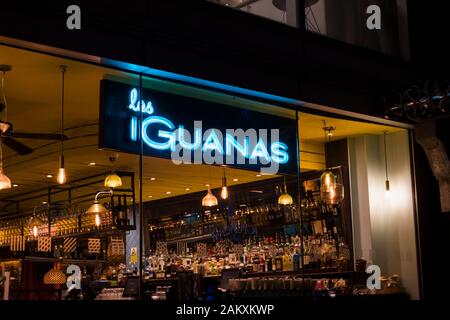 A tarda notte vista dall'esterno del bar chiuso all'interno di Las di iguana ristorante nel centro di Southbank, London SE1 con neon blu accesa nome sign Foto Stock