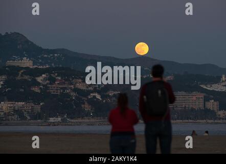 Malaga, Spagna. Decimo gen, 2020. La gente guarda la luna piena (noto come in questo mese come 'Wolf moon") come sorge oltre l'orizzonte in spiaggia durante il primo Eclissi lunare parziale dell'anno. In questo anno 2020 avrà sei eclissi, compreso un eclisse solare totale. Credito: Gesù Merida/SOPA Immagini/ZUMA filo/Alamy Live News Foto Stock