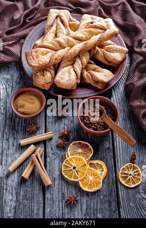 La pasta sfoglia di zucchero Alla Cannella appena sfornata torce su un piatto su un tavolo rustico in legno, vista verticale dall'alto Foto Stock