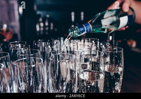 Barman versare champagne in bicchieri da vino sul tavolo Foto Stock