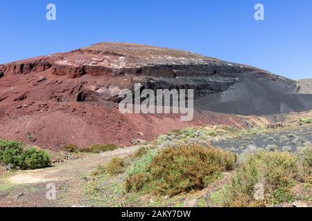 Vista panoramica sulla formazione di rocce vulcaniche di colore rosso e nero nel sud dell'isola delle canarie Lanzarote, Spagna vicino a Playa Blanca con sparse vegetat Foto Stock